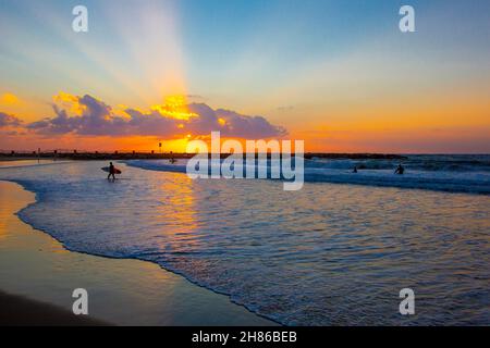 Mediterranean Sunset with surfers in the foreground. Photographed in Tel Aviv, Israel Stock Photo