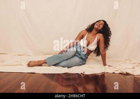 beautiful cheerful girl in jeans and white bra lying on bed Stock Photo -  Alamy