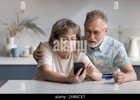 Serious older married couple shopping on internet stores Stock Photo