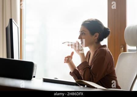 Focused young indian business woman recording audio message on cellphone. Stock Photo