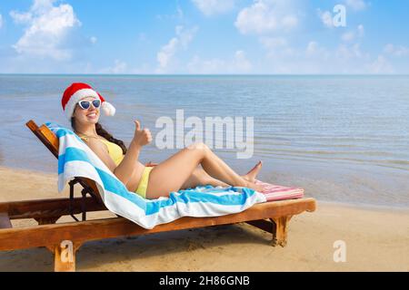 happy young woman in santa hat and sunglasses lying on sun lounger Stock Photo
