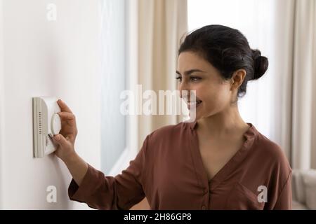 Happy young indian woman setting comfortable temperature. Stock Photo