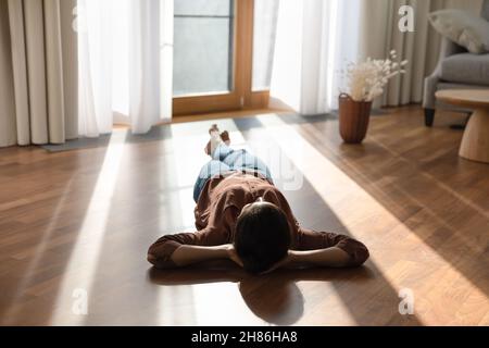 Happy young indian woman lying on warm floor. Stock Photo