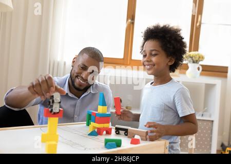 Happy African little son and daddy playing at childish desk Stock Photo
