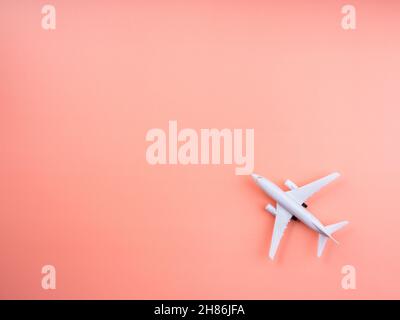 Plane model on pastel pink color background with copy space, top view, minimal style. White airplane, flat lay design. Flight, travel concept. Stock Photo