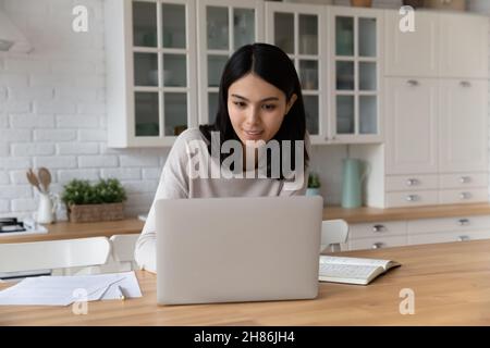 Young Asian woman sit at table working using laptop Stock Photo