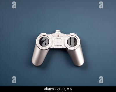 Silver retro style radio remote control for a toy isolated on blue background, top view. Game controller  joystick, flat lay, minimal style. Stock Photo