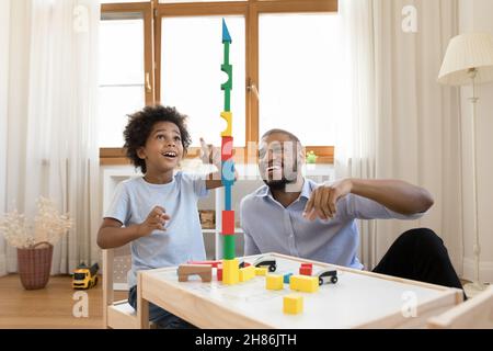 Excited Black little son and happy dad building high tower Stock Photo
