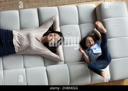 Son have fun on sofa near relaxed mother, above view Stock Photo