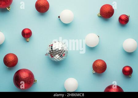 Top view photo of white and red christmas tree balls and glowing disco ball on isolated pastel blue background Stock Photo