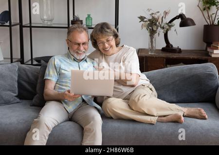 Happy relaxed middle aged couple sitting on couch at home Stock Photo