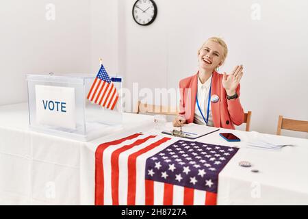 Beautiful caucasian woman working at political campaign waiving saying hello happy and smiling, friendly welcome gesture Stock Photo