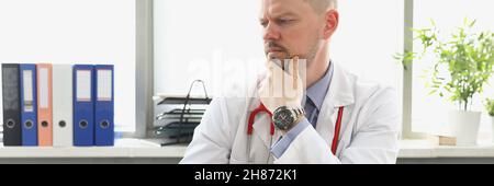 Pensive doctor looking at laptop screen and typing on keyboard in clinic Stock Photo