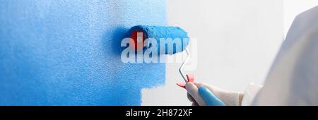 Repairman painting white wall in apartment blue using roller closeup Stock Photo