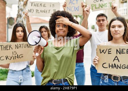 Group of young friends protesting and giving slogans at the street stressed and frustrated with hand on head, surprised and angry face Stock Photo