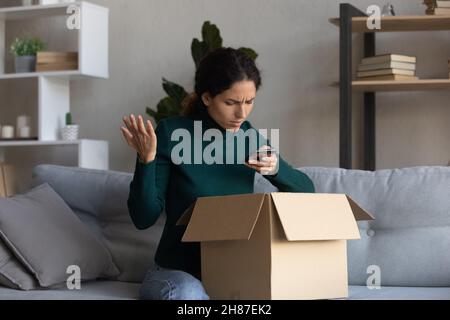 Angry latin female getting wrong order calling delivery to complain Stock Photo