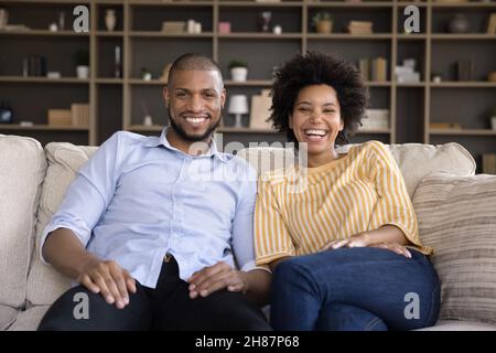 Happy overjoyed young Black couple enjoying leisure in cozy apartment Stock Photo