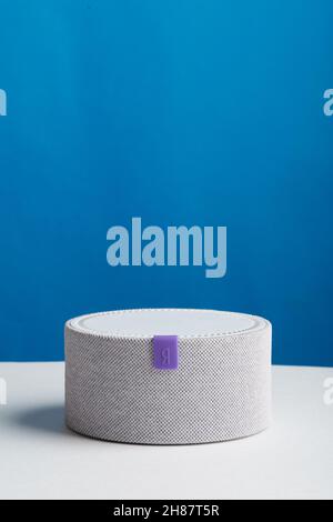 Smart speaker Yandex mini on white table and blue background Stock Photo