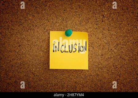 A yellow sticky note with the word Inclusion written on it pinned to a cork board. Close up. Stock Photo