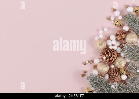 Christmas banner with for branches, cones, golden tree baubles and snowballs on side of pink background with copy space Stock Photo