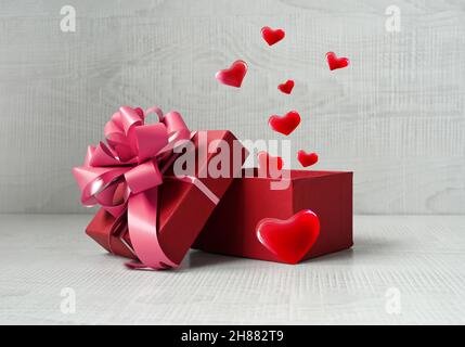 Single red gift box with fireworks from hearts on grey background. Holiday concept. Stock Photo