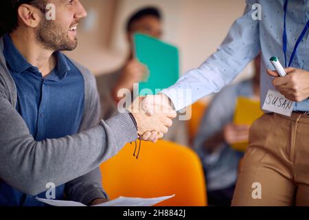 A young male participant is getting know the elderly female lecturer at business lecture in a relaxed atmosphere in the conference room. Business, peo Stock Photo