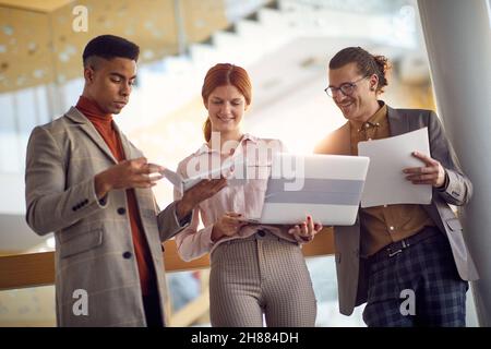 A group of young business people standing in the hallway and doing some work together in a relaxed atmosphere. Business, people, company Stock Photo