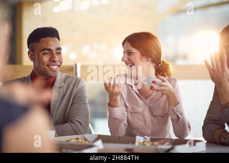A group of young business people enjoying in a friendly conversation in a pleasant atmosphere during a lunch break at work. Business, people, company Stock Photo