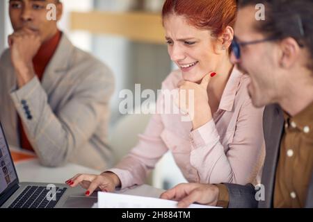 Two young colleagues sitting and watching a laptop content in a relaxed atmosphere at work. Business, people, company Stock Photo
