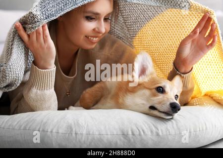 Young woman with cute Corgi dog lying on pouf at home Stock Photo