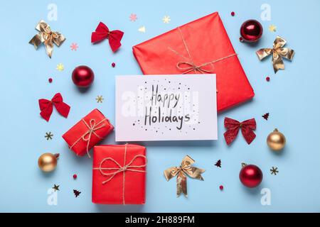 Greeting card with text HAPPY HOLIDAYS, gift boxes and Christmas decor on color background Stock Photo