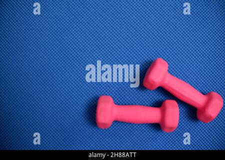 Pink dumbbell on blue yoga mat. Exercise at home using dumbbells for weight control and healthy lifestyle Stock Photo