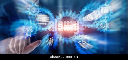 SaaS Software as a Service concept with hand pressing text. Stock Photo