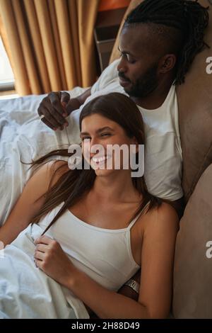 Happy woman and calm man lying in bed Stock Photo
