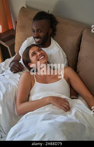 Happy lady and cheerful guy resting in bed Stock Photo