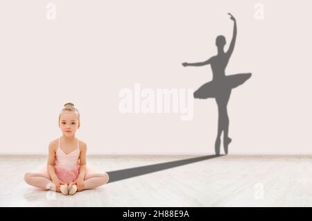 Little ballerina on floor and shape of adult dancer behind Stock Photo