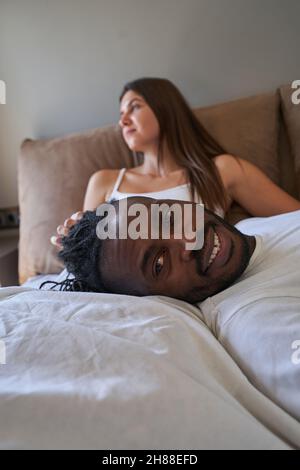 Joyous guy posing for camera with pensive lady on background Stock Photo