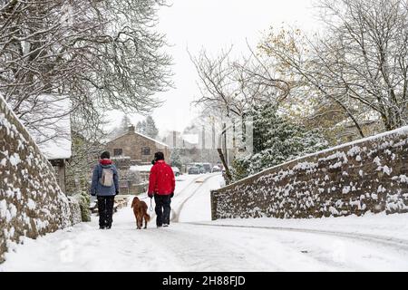 Hardrow, North Yorkshire, 28th November 2021 - Couple taking their dog for a walk in the snow at Hardrow, Wensleydale in the Yorkshire Dales. Most of the areas electricity has been off for more than 36 hours since Storm Arwen struck. Credit: Wayne HUTCHINSON/Alamy Live News Stock Photo