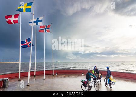 Helsingborg: flags of the nordic countries Iceland, Norway, Sweden, Finland and Denmark, strait Öresund, on island Parapeten, cyclists in , Skane län, Stock Photo