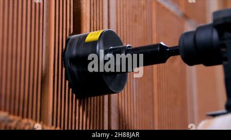 Round nozzle on drill. Stock footage. Professional working drill with round nozzle makes hole in dense brick wall. Close-up of working drill in wall m Stock Photo