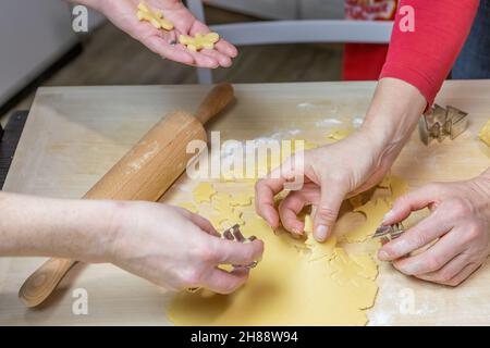 Two women cut out cookies from dough in domestic kitchen, indoors. Horizontally. Stock Photo