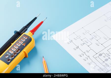Yellow voltage indicator with an electrical diagram on a blue background. Testing and verification of power grids Stock Photo
