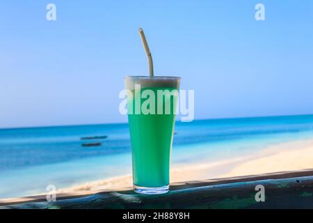 Glass of Blue Hawaii cocktail by the ocean Stock Photo