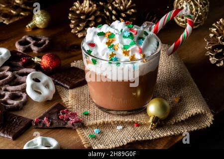 Festive scene of hot chocolate, whip cream and sprinkles served with chocolates.