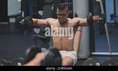 Arab male athlete improves his shoulders with dumbbell breeding. Stock Photo