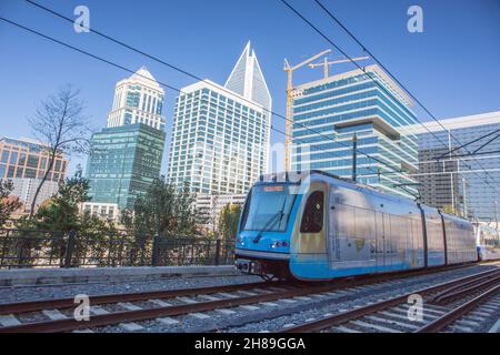 A light rail commuter train in Charlotte, North Carolina, with the uptown skyline in the background. Stock Photo