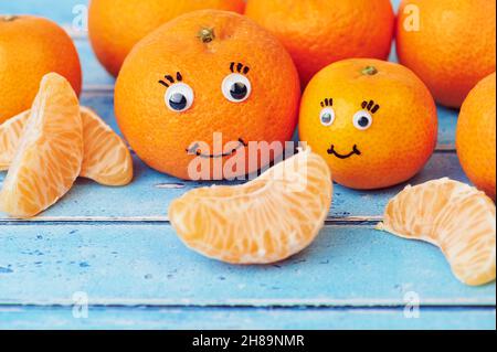 tangerines with funny faces on blue background Stock Photo