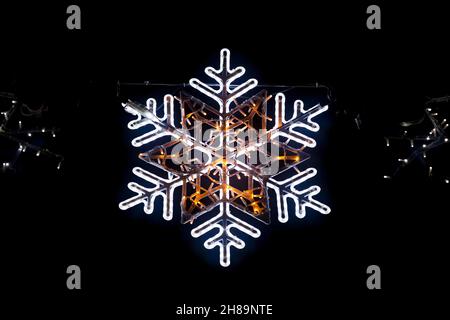 Close-up on an illuminated snowflake light from a Christmas garland. Stock Photo