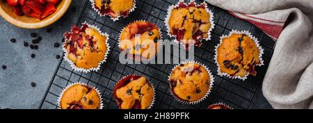 Strawberry chocolate cupcakes muffins on old wooden stand on concrete gray background. Top view. Stock Photo