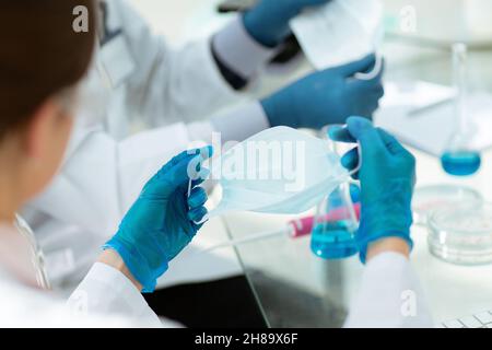 close up. female scientist putting on a protective mask . Stock Photo